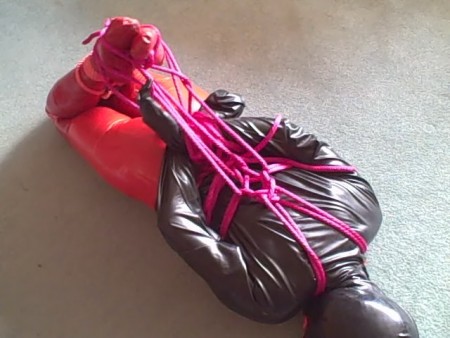 Adreena Hogtied In Rubber - Adreena is dressed from head to toe in rubber. From her fellatio hood, down to her open-crotch tights there is barely an inch of her skin that is not covered with rubber. 
plenty of ropes are woven around her as she lies on the floor, pulling her into a really tight hogtie. Once tied she goes into the hogtie space.  Encouraged to struggle a little in her bondage adreena interprets this as a demand that she tries to escape. Watch her as she struggles for more than 10 minutes to free herself.